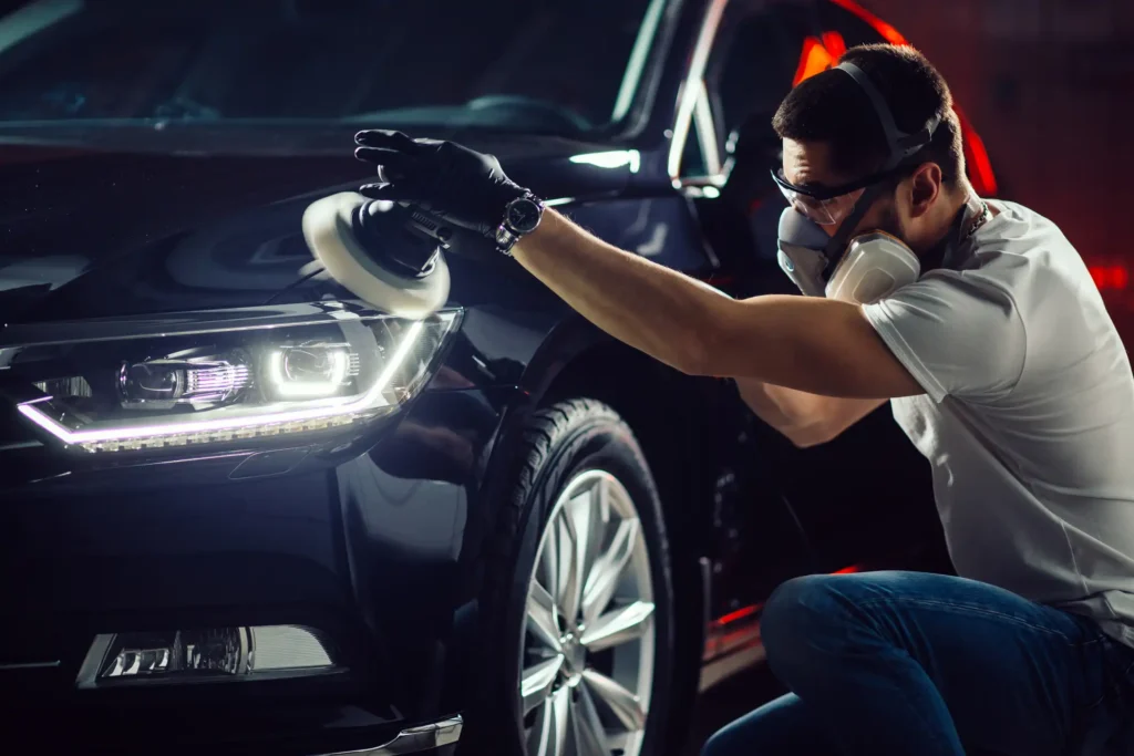Car detailing - Hands with orbital polisher in auto repair shop. Selective focus.