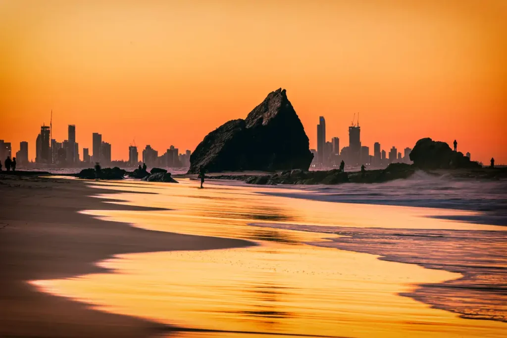 The sunset view of the Currumbin Beach in the twilight and the urban skyline of Gold Coast in the dusk